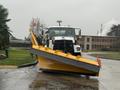 A 2016 Freightliner 108SD truck with a large yellow snow plow attachment in the foreground