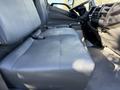 A gray driver's seat in the cabin of a 2014 Hino 195 with a simple and functional design showcasing fabric texture and seatbelt