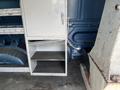 A storage compartment inside a 2009 Ford Econoline with shelves and a locking mechanism