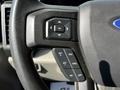 Close-up of a steering wheel control panel featuring buttons for cruise control functions and a central OK button on a 2021 Ford F-550