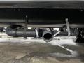 A black pipe system with labeled tags mounted underneath a 2022 Aspen Trail camper featuring a large circular opening and two connecting pipes