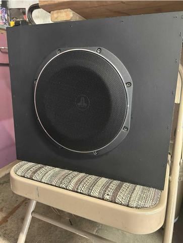 A JL TW10-4 ohm subwoofer with a round black speaker grille mounted on a rectangular black enclosure