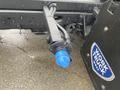 A close-up of a 2021 Ford F-550's tow hitch with a blue connector and a black mounting plate showing a logo for Work Truck West