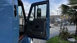 A blue 2009 International 4300 truck with its driver's door open showcasing the interior and side mirror