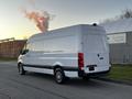 A 2019 Mercedes-Benz Sprinter van in white with black accents parked on a street with a smooth exterior and large cargo space