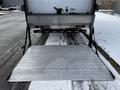 A silver loading ramp extended from the back of a 2019 Hino 338 24 Foot Cube truck with a flat surface and side chains for support