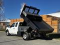 A white 2011 Ford F-350 SD with a raised dump bed displaying its cargo area and a yellow warning light on top