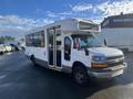 A white 2012 Chevrolet Express bus with multiple windows and a front passenger side door