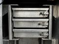 A close-up view of three stacked metallic storage drawers with sliding mechanisms in a vehicle compartment