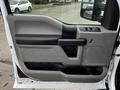 A beige and black door panel of a 2016 Ford F-150 featuring a handle power window controls and a speaker grille