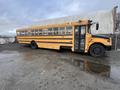 A yellow 2009 International 3000 school bus parked on a gravel surface with visible reflections in puddles on the ground