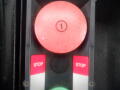 A control panel featuring a large red stop button and two smaller buttons labeled STOP in red