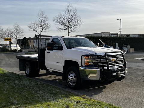 2017 Chevrolet Silverado 3500HD with a flatbed and front grille guard parked on a street