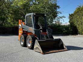 A 2017 Gehl R105 compact skid steer loader with a front bucket and a bright orange and gray exterior