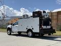 A 2023 Ford F-550 utility truck with a white body features storage compartments and mounted equipment on the truck bed