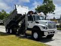 A 2017 International WorkStar 7600 dump truck with a raised bed and a white body featuring black wheels and orange warning lights