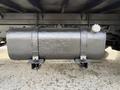 A gray cylindrical fuel tank mounted under a vehicle with two metal clamps securing it in place