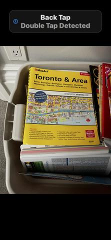 A yellow map titled "Toronto & Area" featuring various local and international maps stacked inside a container