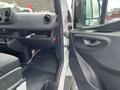 Interior view of a 2025 Mercedes-Benz Sprinter showing the driver's side dashboard and door panel with a comfortable black seat visible