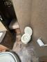 A white toilet is positioned in a bathroom, featuring a closed lid and a nearby toilet paper holder with a roll of toilet paper