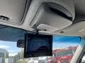 A display monitor is mounted on the ceiling of a vehicle showing a rearview camera feed with parking guidelines