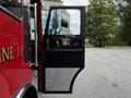 A side view of a 1991 Sutphen Deluge fire truck with the driver's door open revealing the interior door panel and handle