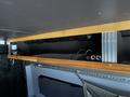A 2017 Mercedes-Benz Sprinter with a wooden overhead storage compartment containing various items and tools