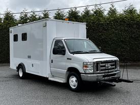 A silver 2013 Ford Econoline with a large white cargo area and a front-mounted hitch attachment