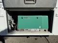 A green Cummins Onan generator with a silver base displayed in an open compartment of a vehicle