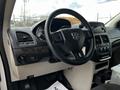 Interior view of a 2011 Dodge Grand Caravan featuring a steering wheel with logo dashboard controls and a center console with audio and climate controls