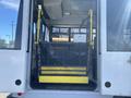 A yellow wheelchair lift is positioned at the back entrance of a 2017 Chevrolet Express bus