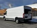 A white 2017 RAM Promaster van with a high roof and rear doors facing the viewer parked on an industrial street