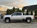 A 2023 Chevrolet Silverado 3500HD in silver with a crew cab and chrome wheels parked on a concrete surface