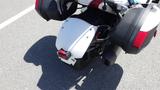 A 2013 Can-Am Spyder with a white rear body and black saddlebags showcasing the taillight and exhaust pipe