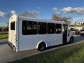 A white 2017 Chevrolet Express shuttle bus with large windows and an open door, showing a spacious interior designed for passenger transport