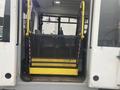 A yellow and black wheelchair lift installed at the back of a 2017 Chevrolet Express van with a mesh enclosure and safety handles