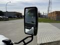 A side mirror of a 2010 Ford Econoline reflecting part of the vehicle and the surroundings in its glass