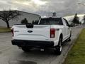 A white 2016 Ford F-150 pickup truck viewed from the rear with a four-wheel drive badge on the tailgate and chrome accents on the bumper