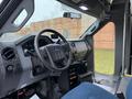 Interior of a 2011 Ford F-550 featuring a steering wheel control panel and a blue upholstered driver's seat