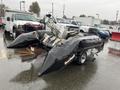 A 2009 ShoreLandr ANDER boat trailer with a white outboard motor mounted on top and black inflatable pontoons on either side sitting in a wet parking lot