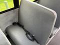 A gray bus seat with a safety belt is shown in the foreground