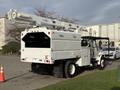 A 2011 International 4300 utility truck equipped with a white Altec aerial lift on the back and a flatbed storage area