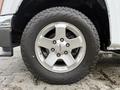 Close-up of a silver alloy wheel with a red GMC emblem and all-terrain tire tread on a 2012 GMC Canyon