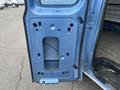 A blue metal door panel from a 2010 Ford Econoline showing various cutouts and mounting points for hardware and a window
