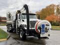 A 2014 International 7500 truck with a large vacuum tank and hose attached in the front for suction and debris removal