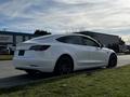 A white 2019 Tesla Model 3 parked on the roadside showcasing its sleek design and modern features