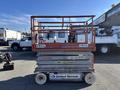 A 2010 Skyjack SJ scissor lift with a raised platform and orange frame displaying rental company logos and a clear work area below