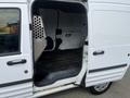 A 2010 Ford Transit Connect with an open side door revealing an empty interior and a protective metal partition