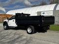 A 2018 Ford F-550 truck with a white cab and a black flatbed, parked and viewed from the side
