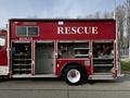 A red 1994 Freightliner FL80 rescue truck with compartments open revealing equipment and hoses inside